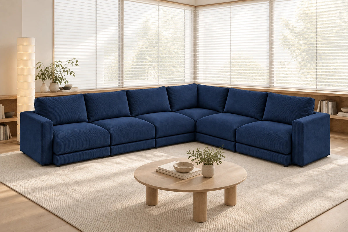 Sofá modular rinconero en L, composición L-3-2, tapizado en pana fina azul, en un salón luminoso con madera clara y tonos naturales.