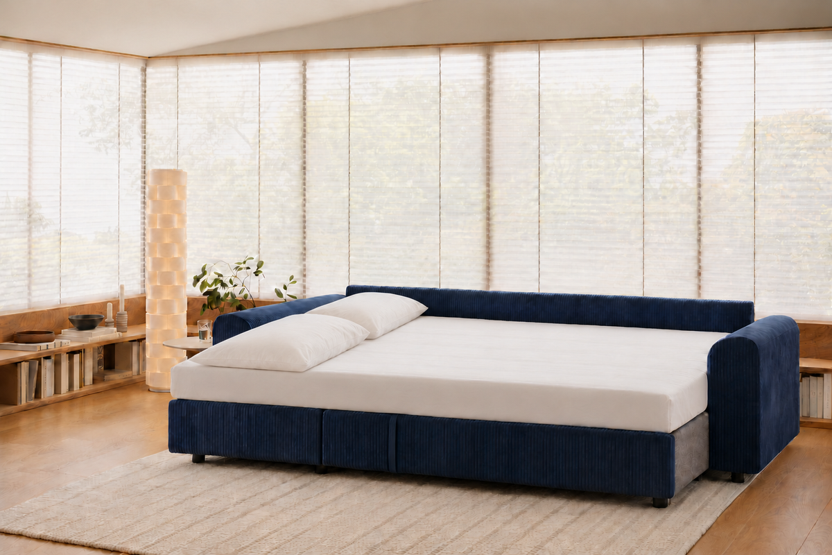 Tria convertido en cama, con sábana bajera y dos almohadas, en un salón.
