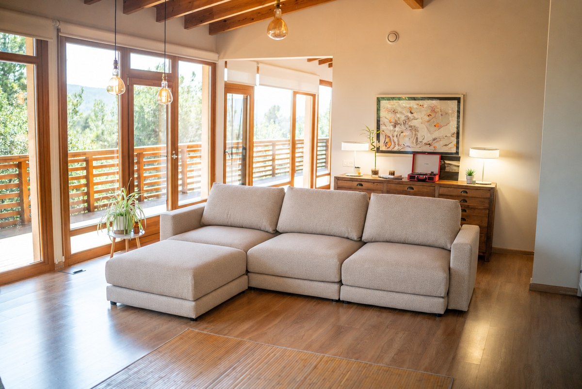 Sofá Modular beige de tres módulos con un puff independiente en un salón real